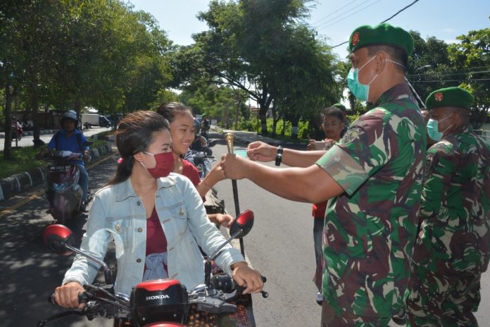 BAGI MASKER: Pembagian masker ke para pengguna jalan di Jalan dr Seodjono depan Makorem 162/WB, Rabu (1/4).(Dery Harjan/Radar Lombok)