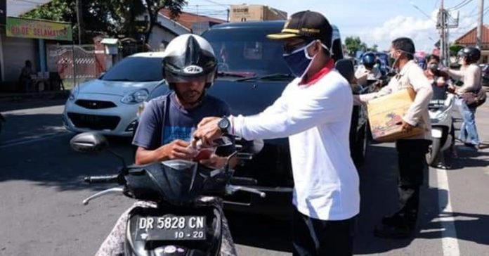 BAGIKAN MASKER: KPU Kota Mataram melalukan pembagian masker kepada pengguna jalan di simpang empat Jalan Gadah Mada, Jempong, Mataram, Rabu (21/4) kemarin.)( IST FOR RADAR LOMBOK)