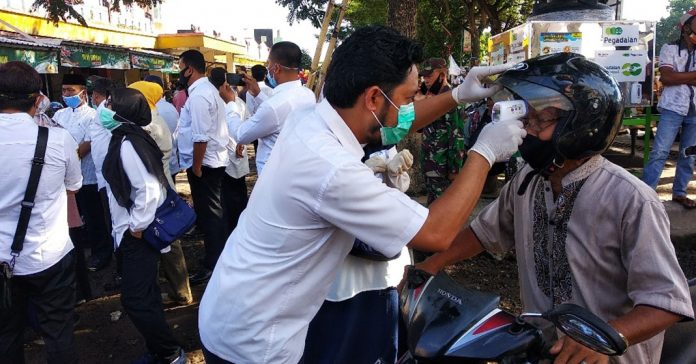 CEK SUHU: Petugas Kesehatan Lombok Barat saat mengecek suhu salah seorang pengunjung pasar Kediri saat turun memantau kedisplinan masyarakat bersama Bupati Lombok Barat, H Fauzan Khalid, kemarin.( ZULFAHMI/RADAR LOMBOK)