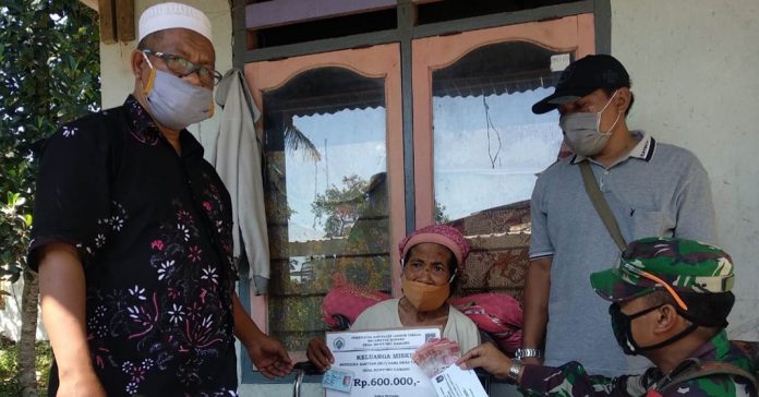 BANTUAN BLT : Kepala Desa Montong Gamang Kecamatan Kopang Lombok Tengah, HM Amin Abdullah saat menyalurkan BLT ke salah seorang masyarakat yang lanjut usia. (Faesal Haris/ radalombok.co.i)