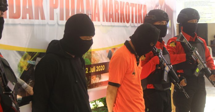 Tersangka SR alias Tio ( tengah) dikawal petugas saat diperlihatkan di Mapolresta Mataram, Kamis( 2/7) (Dery/radar lombok)