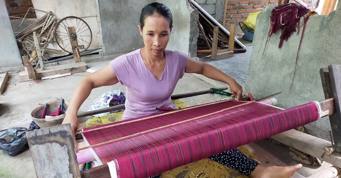 TENUN: Kerajinan tangan menjadi salah satu pendukung dan pengembangan pariwisata di NTB. Tampak salah seorang penenun asal Kabupaten Lombok Utara sedang menenun kain khas daerah itu. (HERY MAHARDIKA/RADAR LOMBOK)