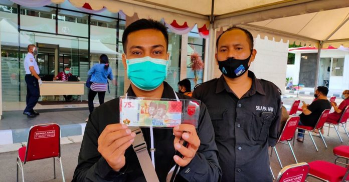 UANG KEMERDEKAAN : Salah seorang warga kota mataram menunjukkan uang kertas edisi khusus kemerdekaan Rp. 75.000