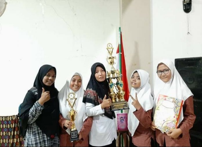 PRESTASI : Siti Surodiana SP bersama siswanya pada saat mengangkat medali penghargaan yang diraih pada lomba karya ilmiah guru yang digelar di Unesa Jawa Timur tahun 2019 lalu. (Janwari Irwan/Radar Lombok)